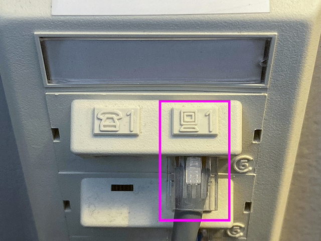 Quad port wall plate, showing the top left connector labeled with a computer icon, and an Ethernet cable plugged into it. This port is highlighted with a pink square.